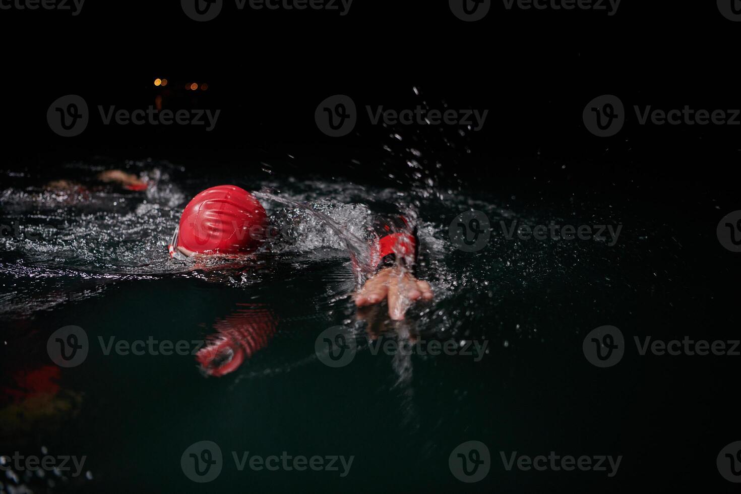 A determined professional triathlete undergoes rigorous night time training in cold waters, showcasing dedication and resilience in preparation for an upcoming triathlon swim competition photo