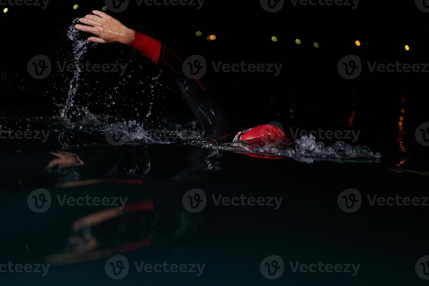 A determined professional triathlete undergoes rigorous night time training in cold waters, showcasing dedication and resilience in preparation for an upcoming triathlon swim competition photo