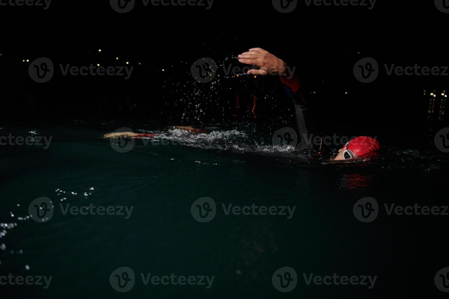 A determined professional triathlete undergoes rigorous night time training in cold waters, showcasing dedication and resilience in preparation for an upcoming triathlon swim competition photo