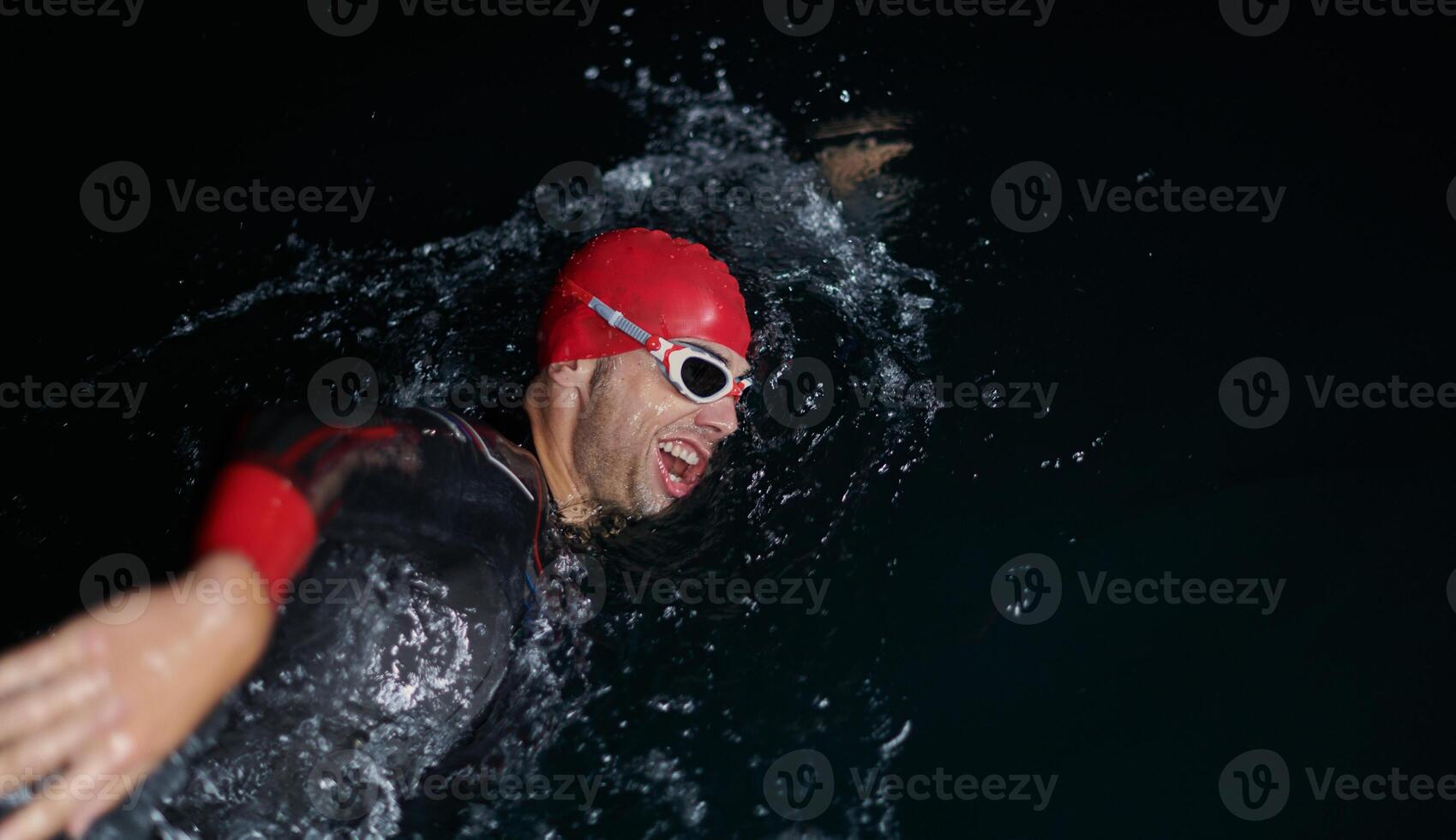 A determined professional triathlete undergoes rigorous night time training in cold waters, showcasing dedication and resilience in preparation for an upcoming triathlon swim competition photo