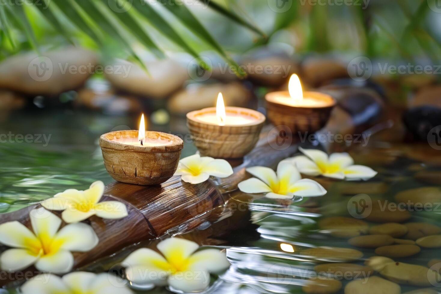 Three burning cosmetic candles on a bamboo stand, tropical flowers and leaves reflected in the water, sun bokeh, relaxation spa background photo