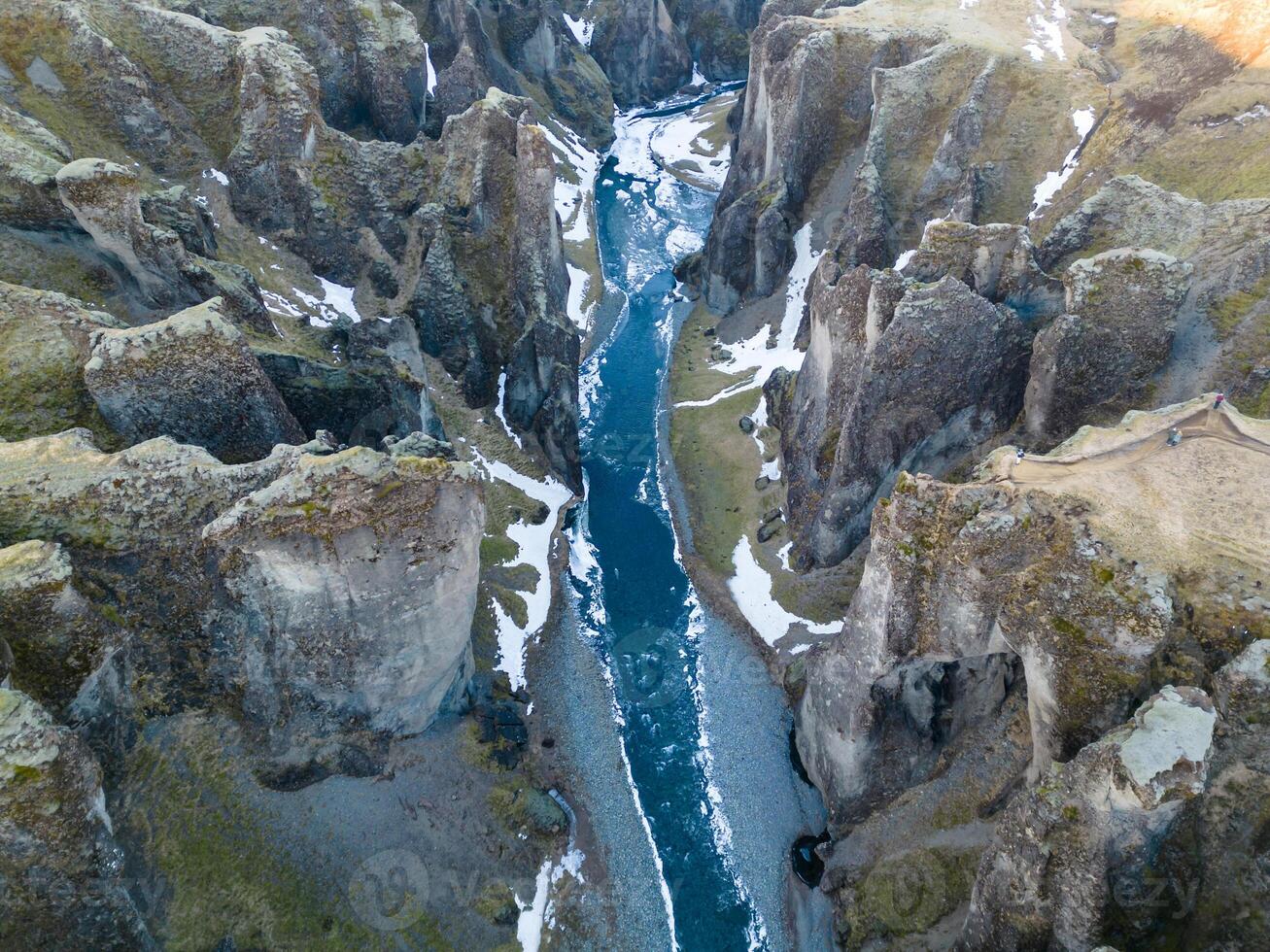 Drone shot of snowy icelandic canyon with frozen water stream and mountains covered in frost creating gorgeous scenery. Magical fjadrargljufur canyon with river in iceland, sightseeing. photo