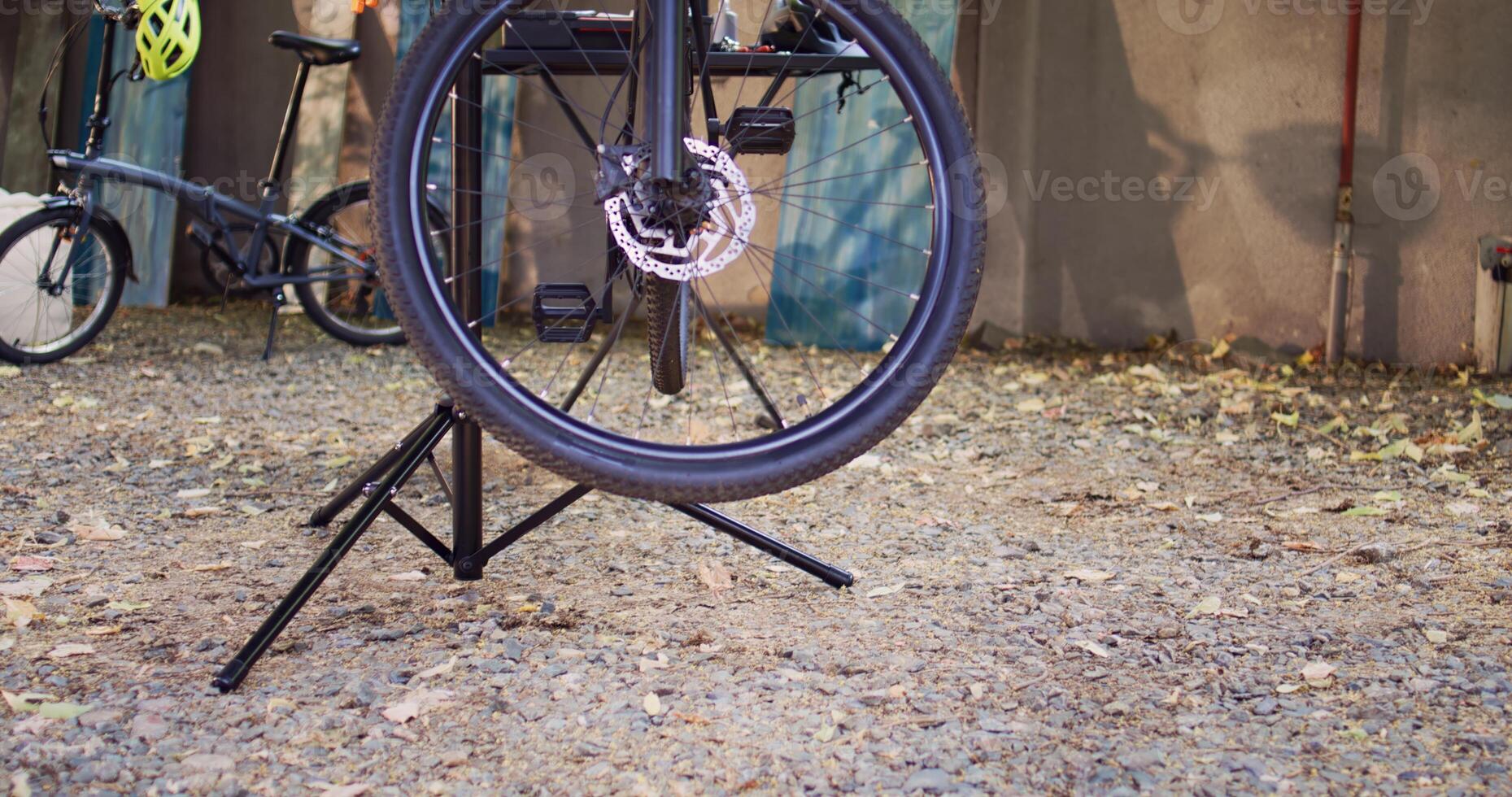 Detailed view of damaged bike mounted on repair-stand ready for repair with assortment of tools outdoor. Annual summer upkeeping and servicing of modern bicycle in home yard. photo