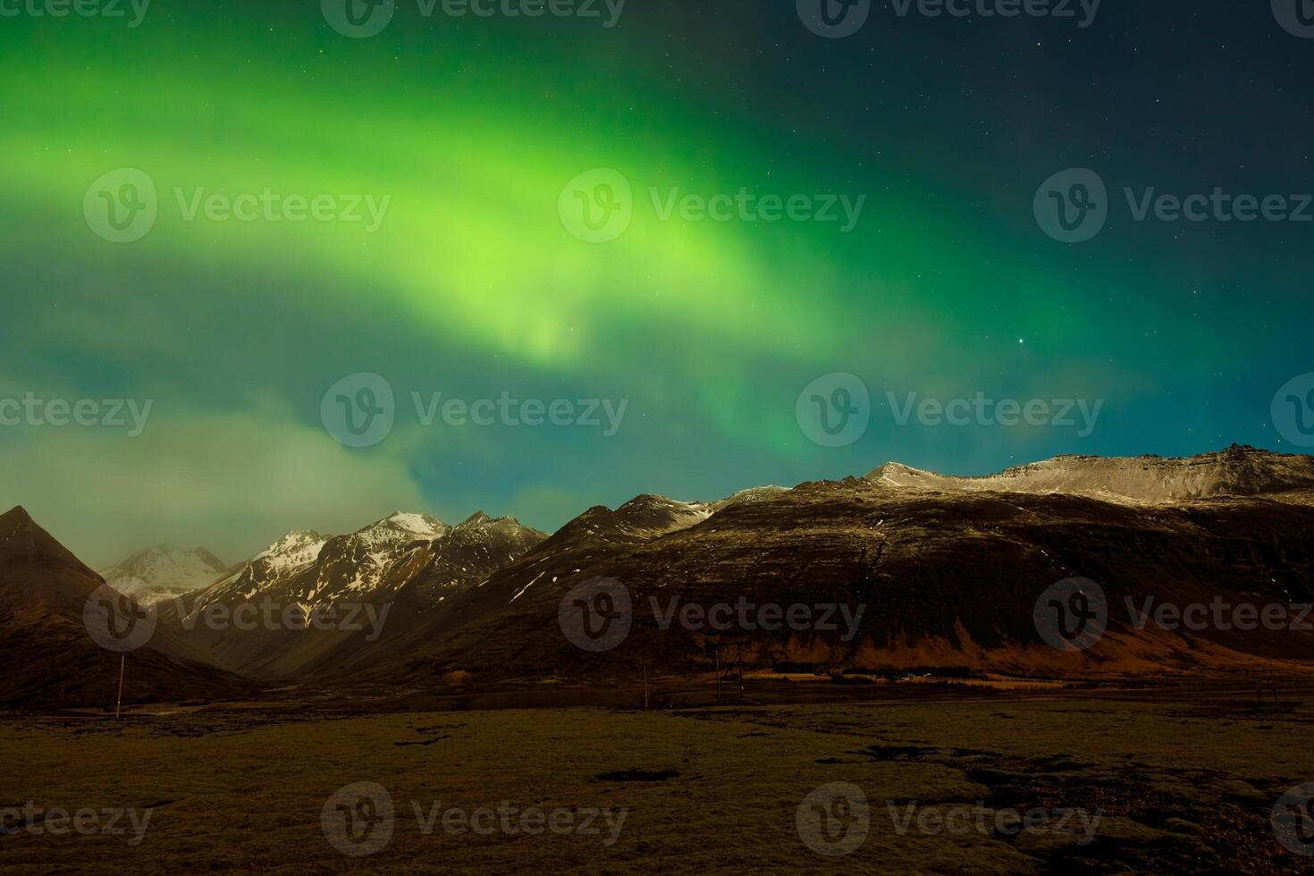 Wintry landscape with aurora borealis above snow covered mountain peaks. Icelandic northern lights magnificent natural phenomenon that brighten up sky, arctic region with magic reflections. photo