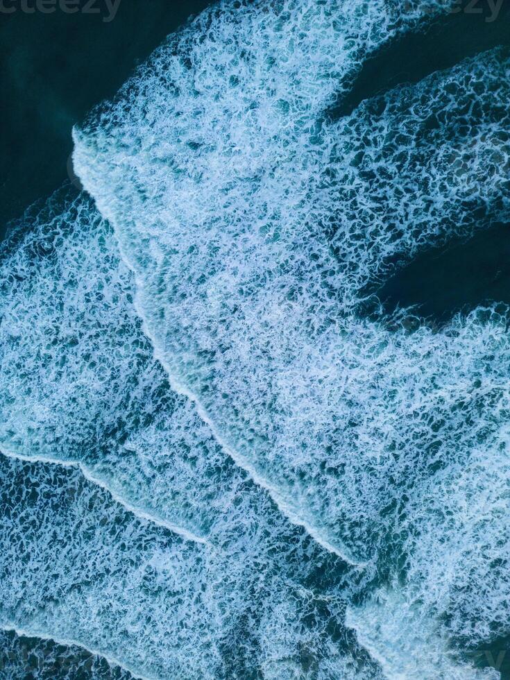Iceland scenery black sand beach on atlantic ocean coastline, majestic northern country with natural freezing cold setting. Drone shot of icelandic nature with waves hitting the beachfront. photo