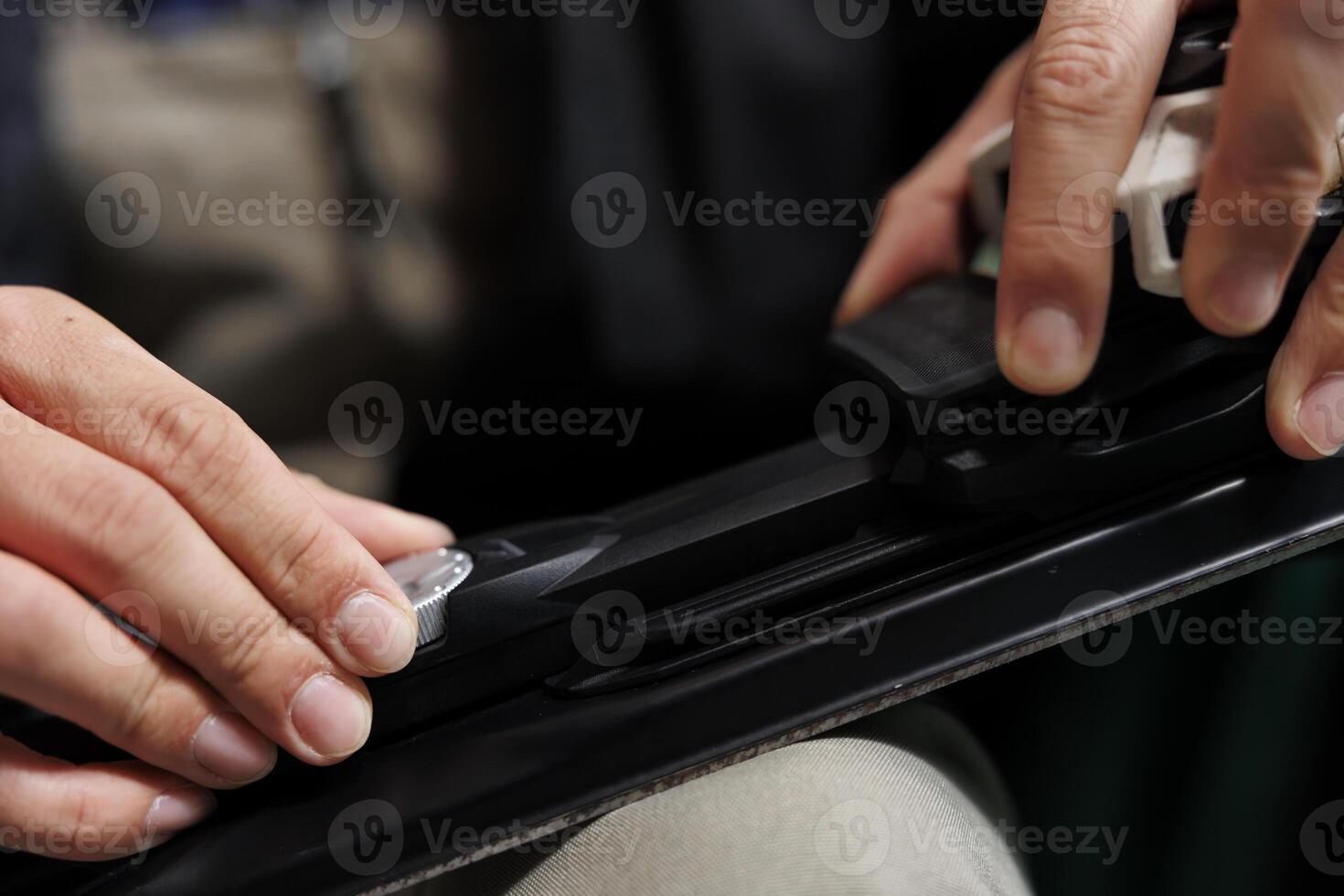 Detailed shot of pair of hands modifying skiing skis in preparation of wintersports activities. Ski equipment being adjusted and maintained by a person in lounge area of winter resort. photo