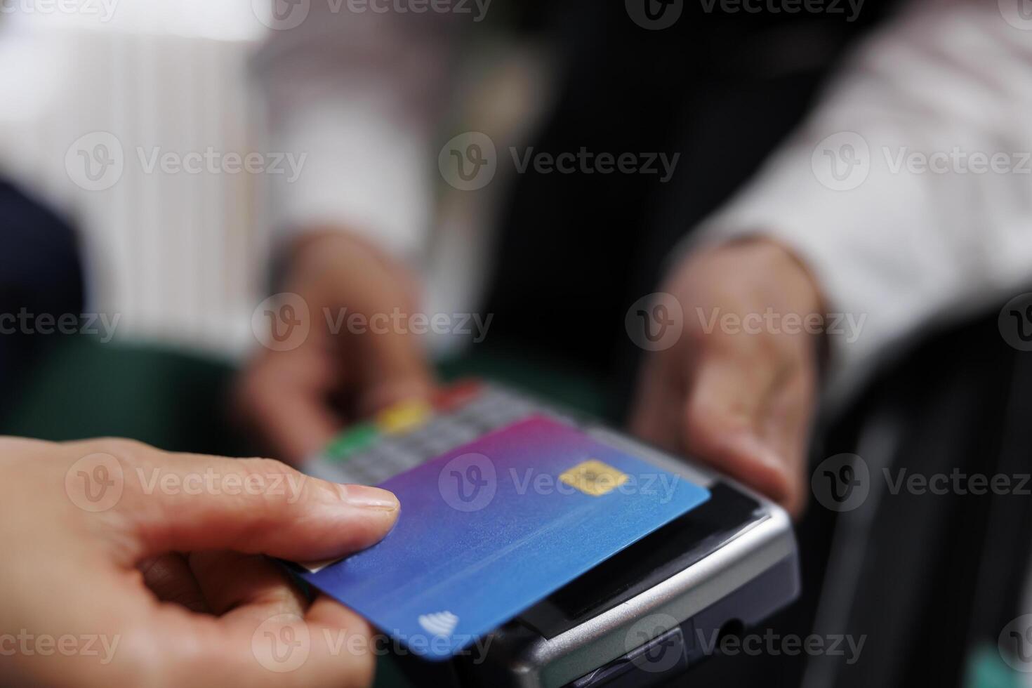 Detailed view showing hands of hotel employee holding pos terminal towards tourist paying with debit card. Close-up of cashless payment using credit card machine at lounge area of ski resort. photo