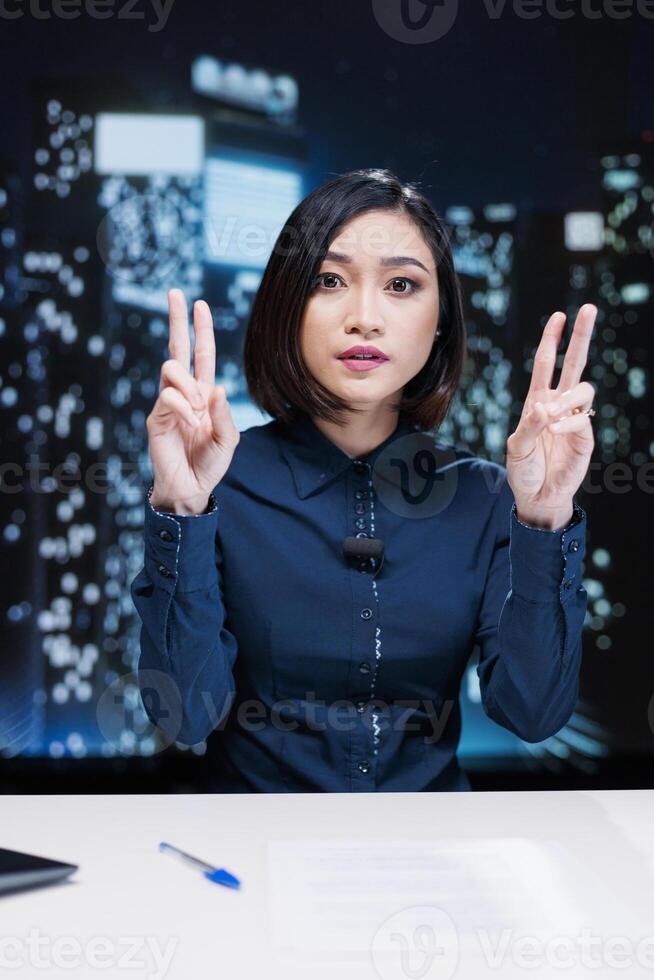 Asian reporter debating breaking news topics live on media network, reading headlines of the day to create exclusive content for midnight talk show. Woman presenter doing tv newscast. photo