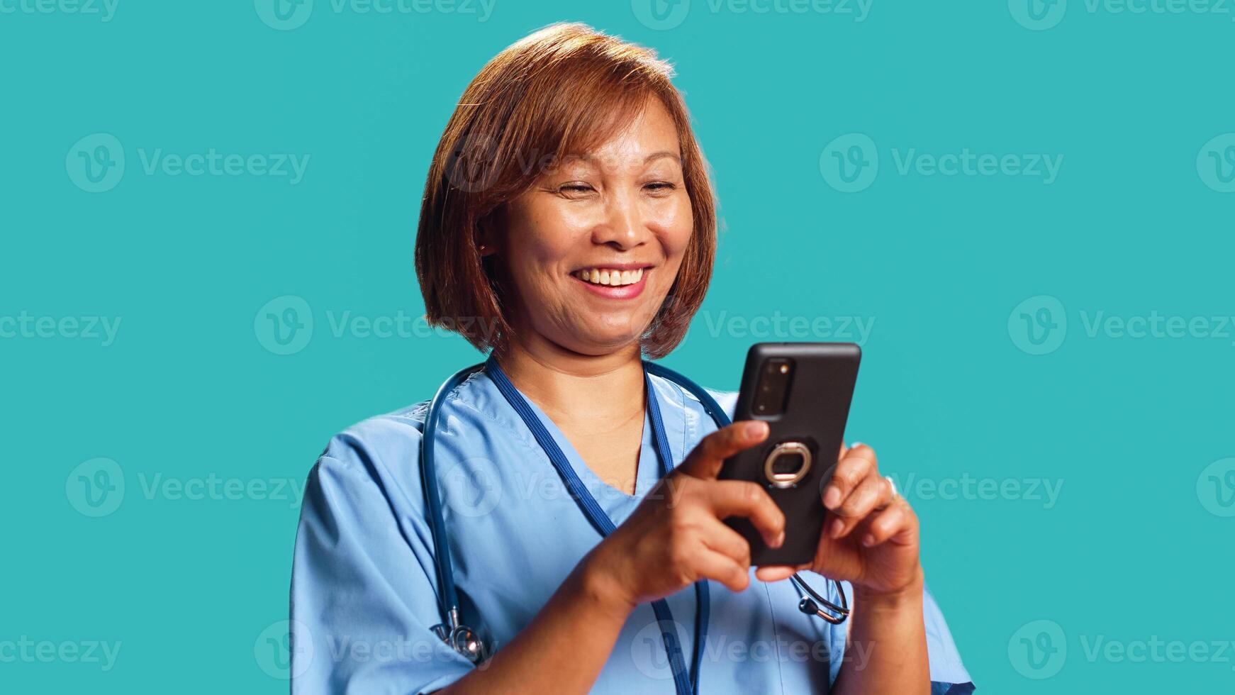 Jubilant nurse having burst of joy at work while chatting with friends, isolated over studio background. Elated hospital worker delighted about great news she received over the phone, close up photo