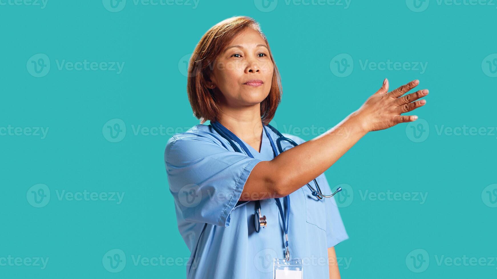 Close up shot of clinic worker doing swiping hand motion gestures, remotely controlling digital screen. Experienced nurse isolated over blue studio background working in high-tech modern hospital photo