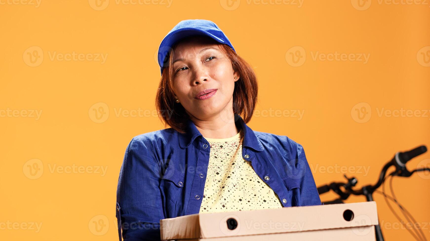 Hasty BIPOC employee waiting for client to answer door and pick up meal order. Portrait of bored courier isolated over studio background carrying stack of pizza boxes, close up photo
