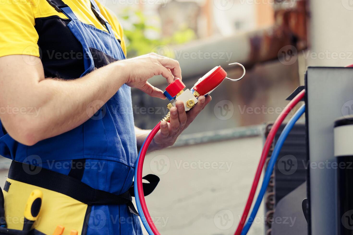 Experienced wireman doing annual air conditioner maintenance, assembling pressure measurement device before starting work. Licensed serviceman refilling cooling system refrigerant tank photo
