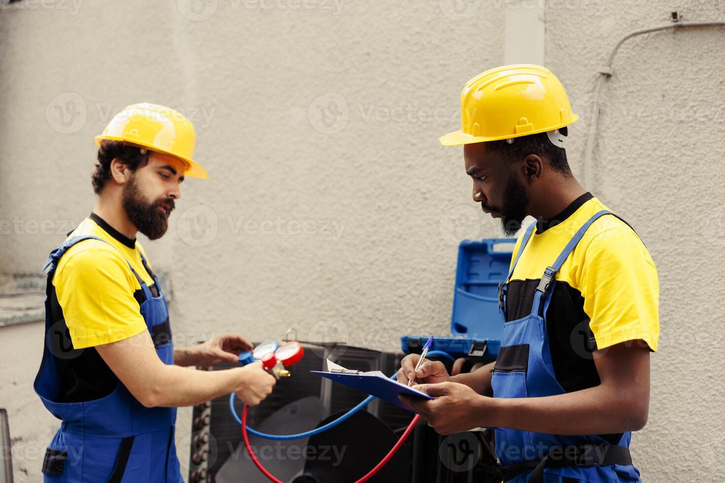 Trained engineer using set of manometers to read pressure of liquids and gases in condenser unit while expert repairman writes air conditioner faulty components report list on clipboard photo