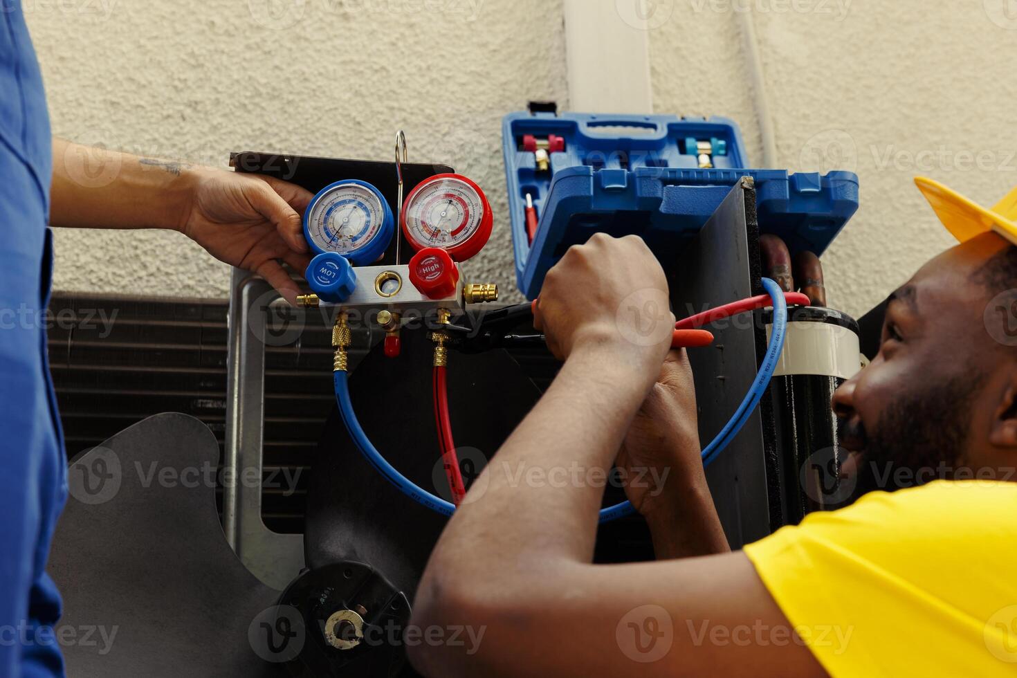 Seasoned mechanics commissioned by client to do maintenance on hvac system, repairing broken manifold gauges. Precise servicemen refilling freon tank after patching up leak photo