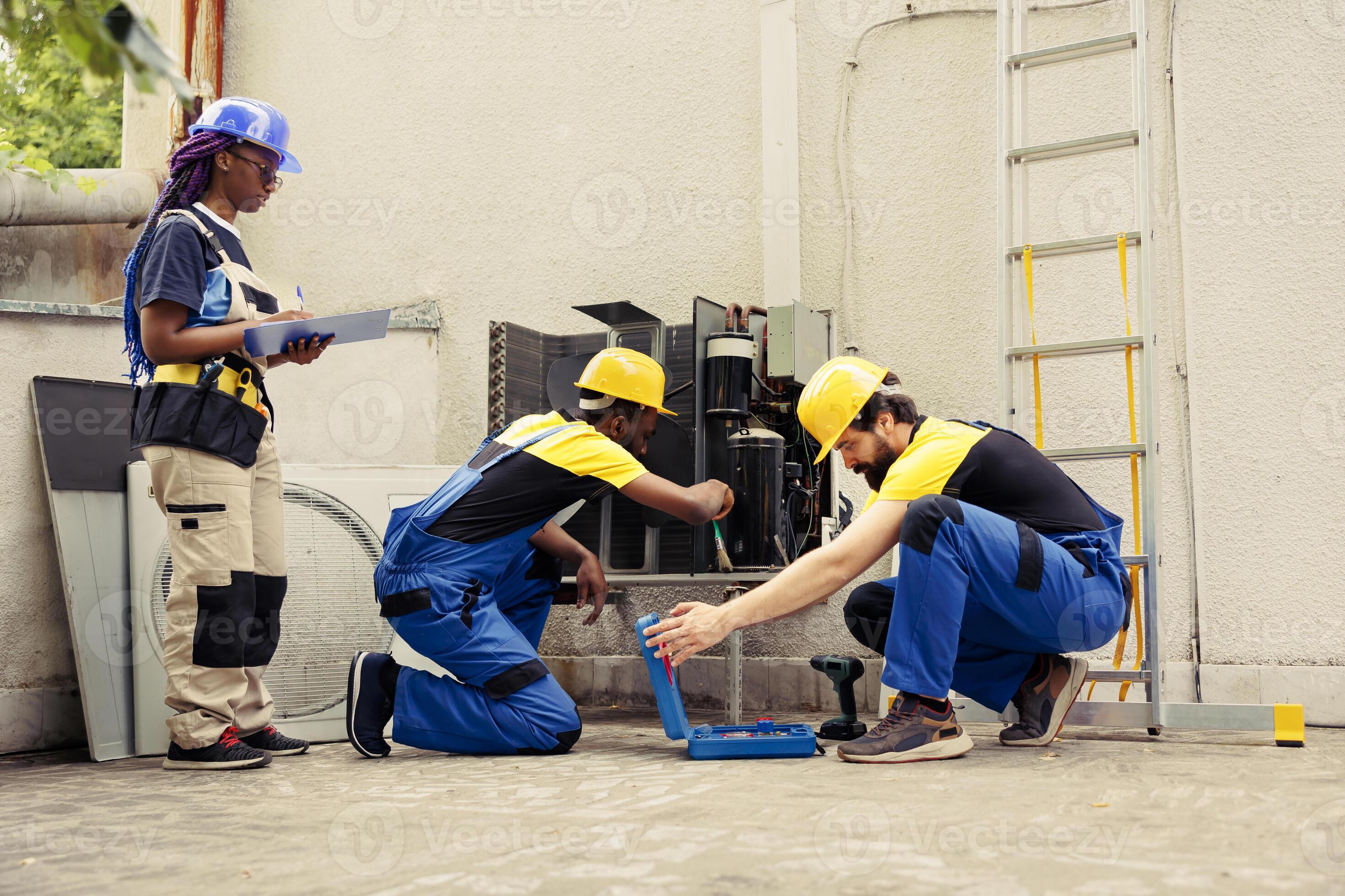 Diverse crew contracted by home owner to fix broken air conditioner. Coworking mechanics