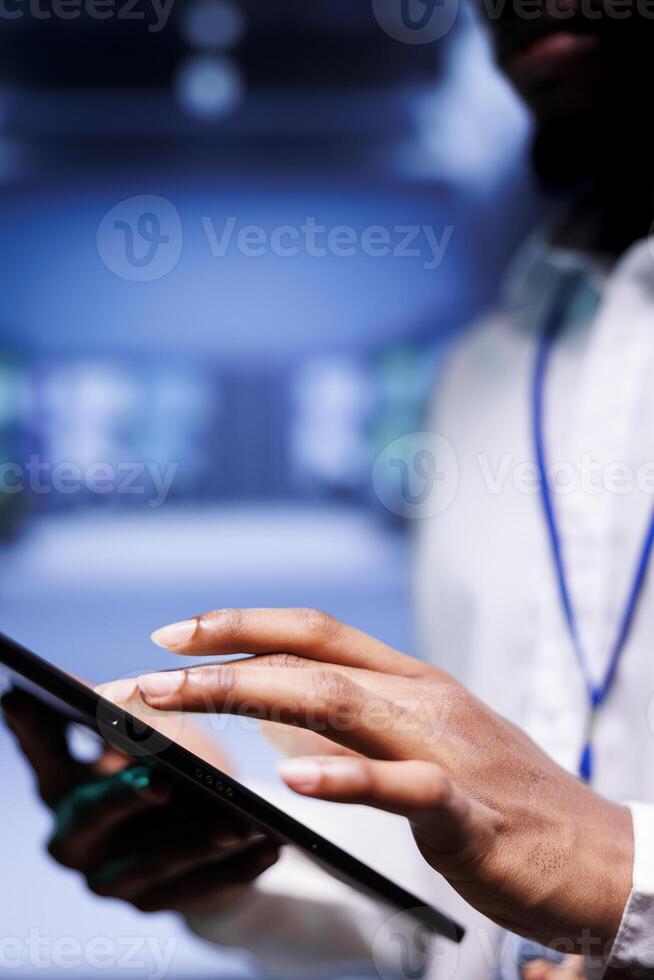 Close up of system admin working in computer network security data center, ensuring optimal performance. Worker monitoring energy consumption across operational server racks components photo