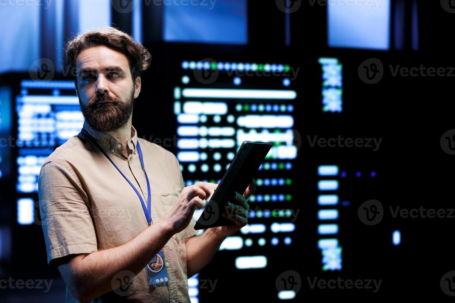 Repairman doing routine system servicing, imputing data on tablet of required upkeeping in server rigs housing advanced data storage infrastructure supporting critical IT workloads photo