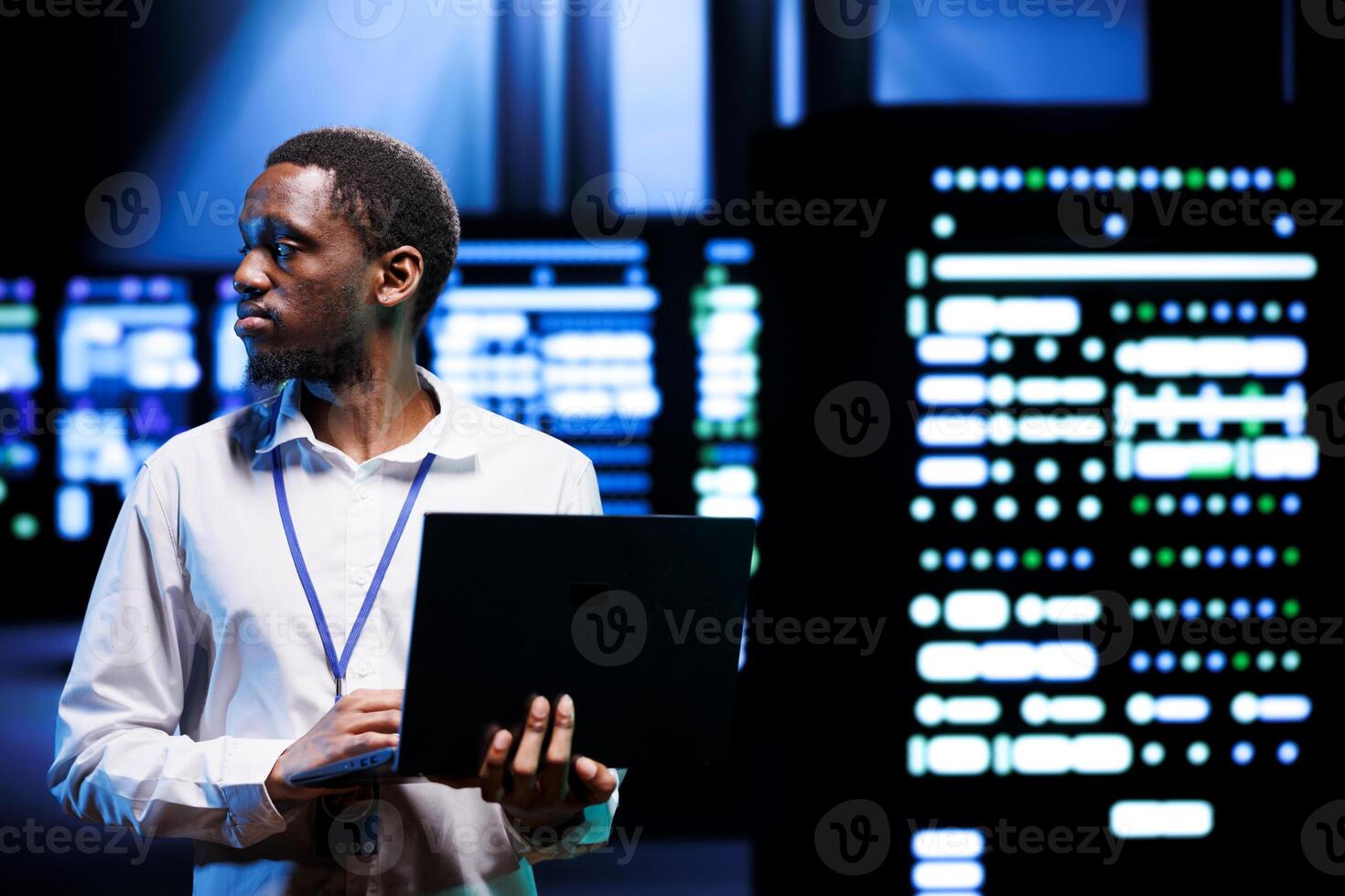 IT developer in server room using laptop to find firewall misconfigurations affecting mainframes performance and connectivity, leading to sluggish data transfer rates and poor client communication photo