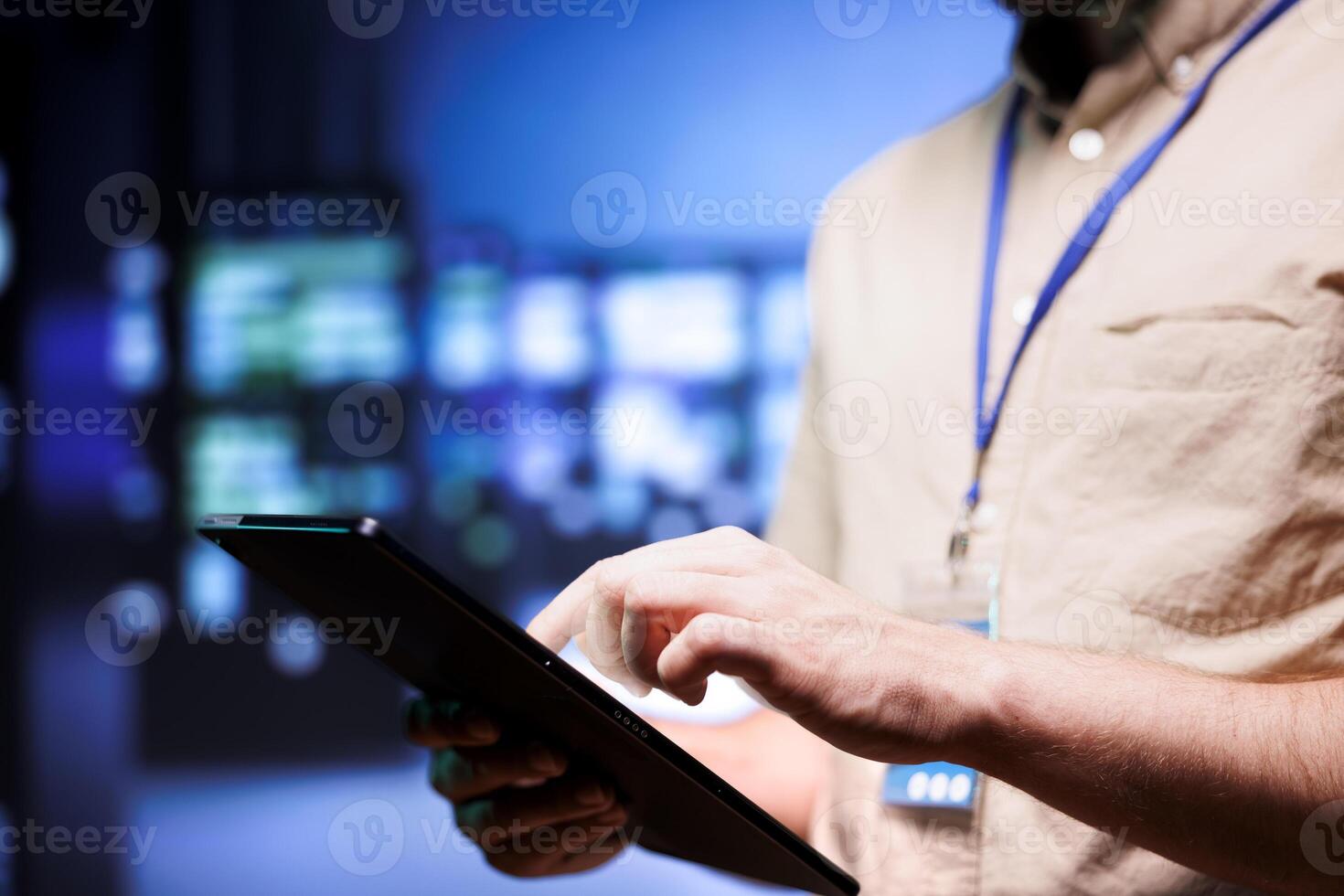 Electrician in server farm between supercomputers used for computationally intensive tasks such as scientific simulations or 3D rendering. Wireman doing routine equipment checkup using tablet photo