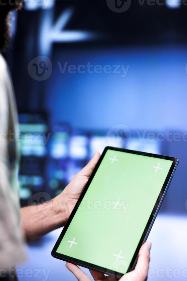 Technical support executive solving performance issues of data center mainframes. Manager utilizing chroma key tablet to identify establishment operational problems causing hardware slowdown. photo