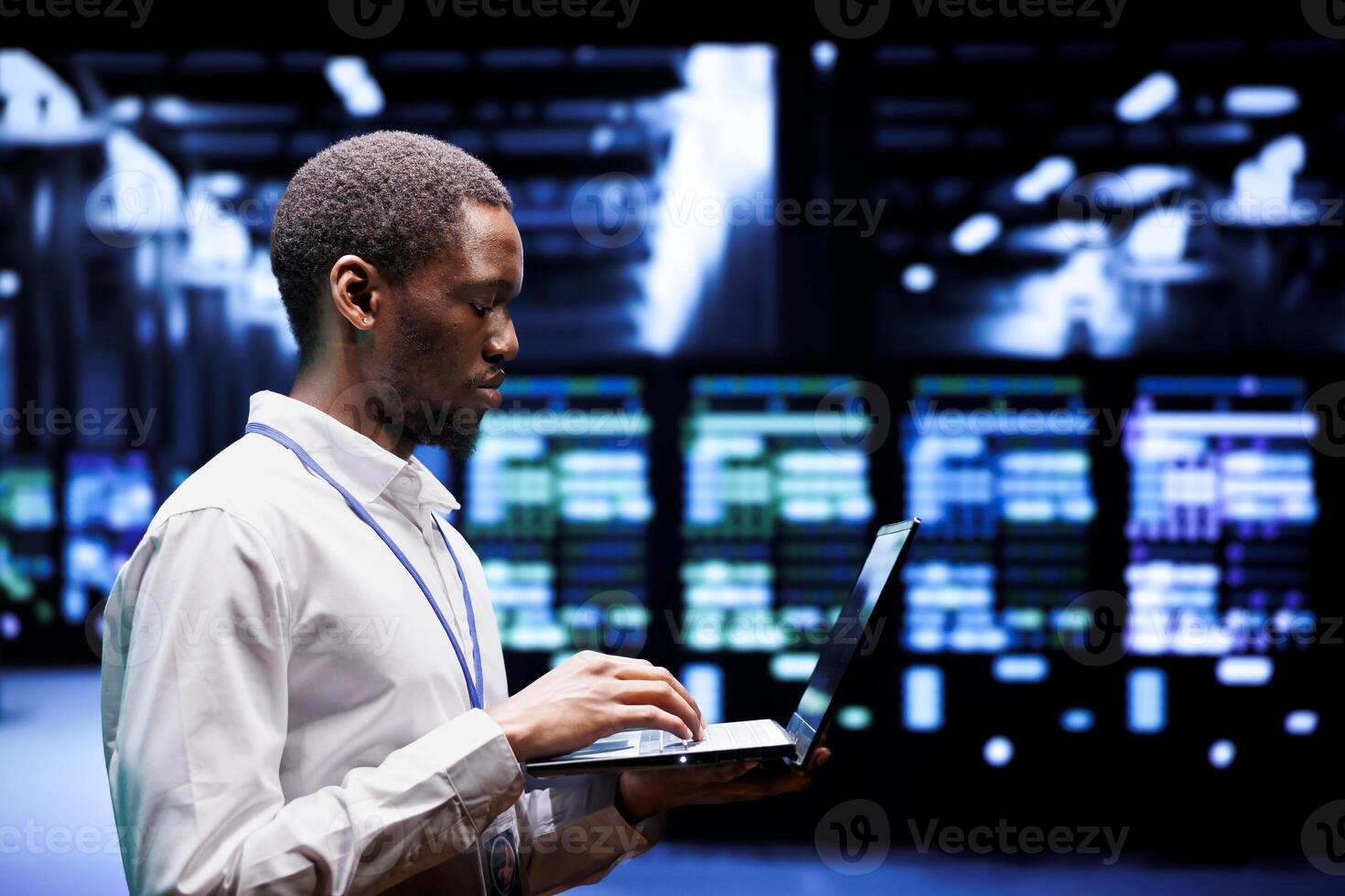 African american system administrator typing supercomputer hub contingency plan on laptop to provide fast restoration of service, limiting damage and minimizing interruptions to normal operations photo