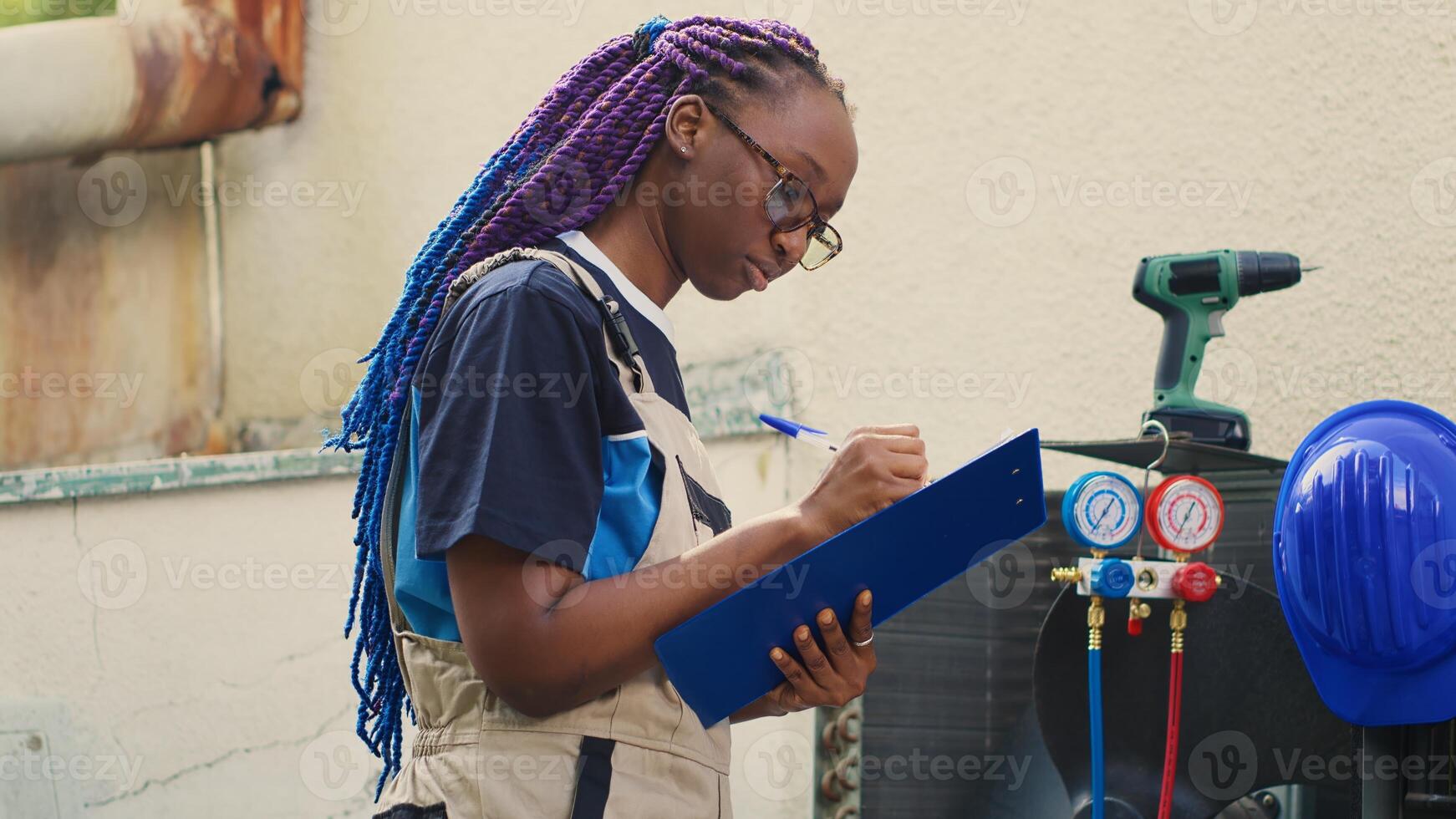 Portrait of cheerful african american wireman commissioned for hvac system routine check up, writing report on clipboard. Worker doing condenser inspection, looking for faulty components photo
