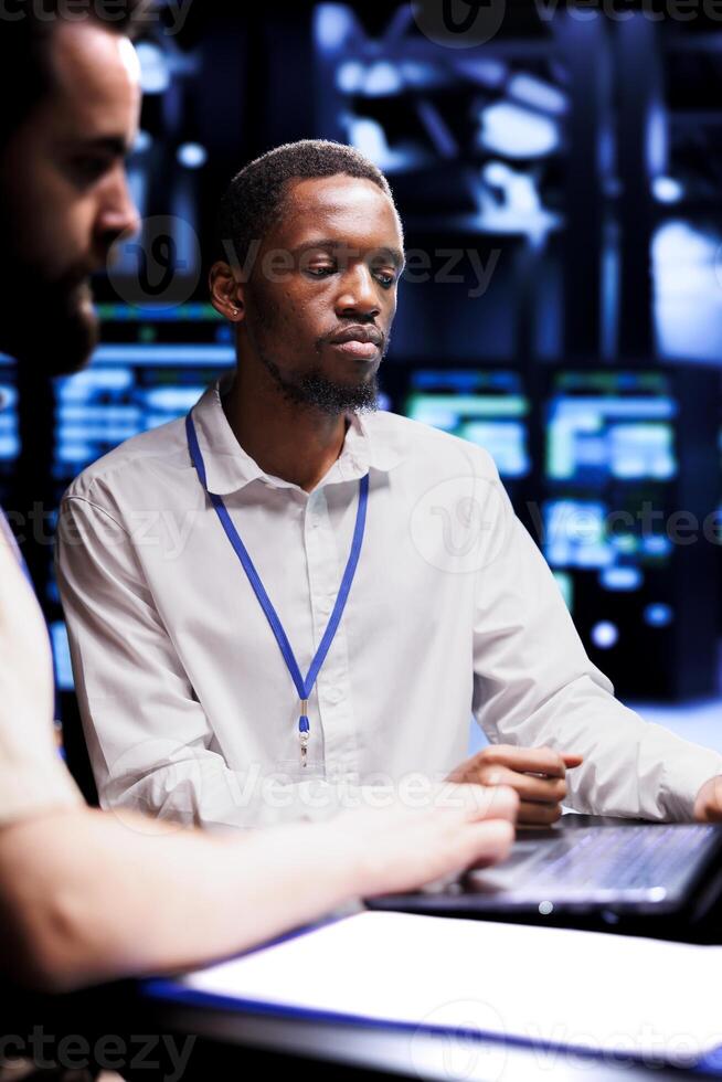 African american admin and coworker dealing with server farm system failures. Colleagues brainstorming ideas on how to best minimize supercomputers downtime and prevent crashes photo