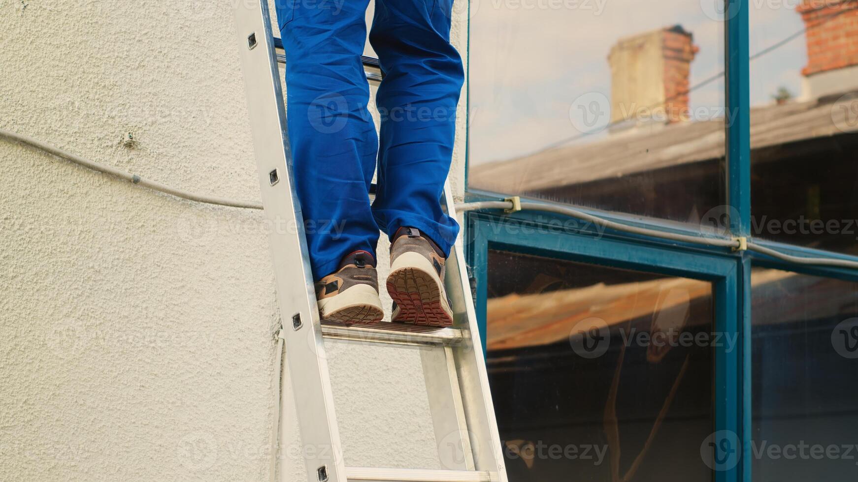 Certified technician holding cordless drill, stepping down from folding ladder after finishing checkup on rooftop condenser. Skilled expert at the end of maintenance assignment photo
