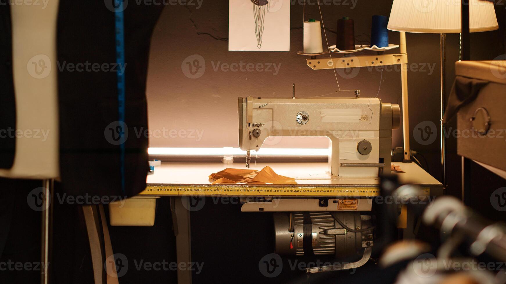 Sewing machine in tailor workshop, industrial fashion atelier with tailoring equipment used for custom made clothes. Textile industry with professional tools and workstations. Close up. photo