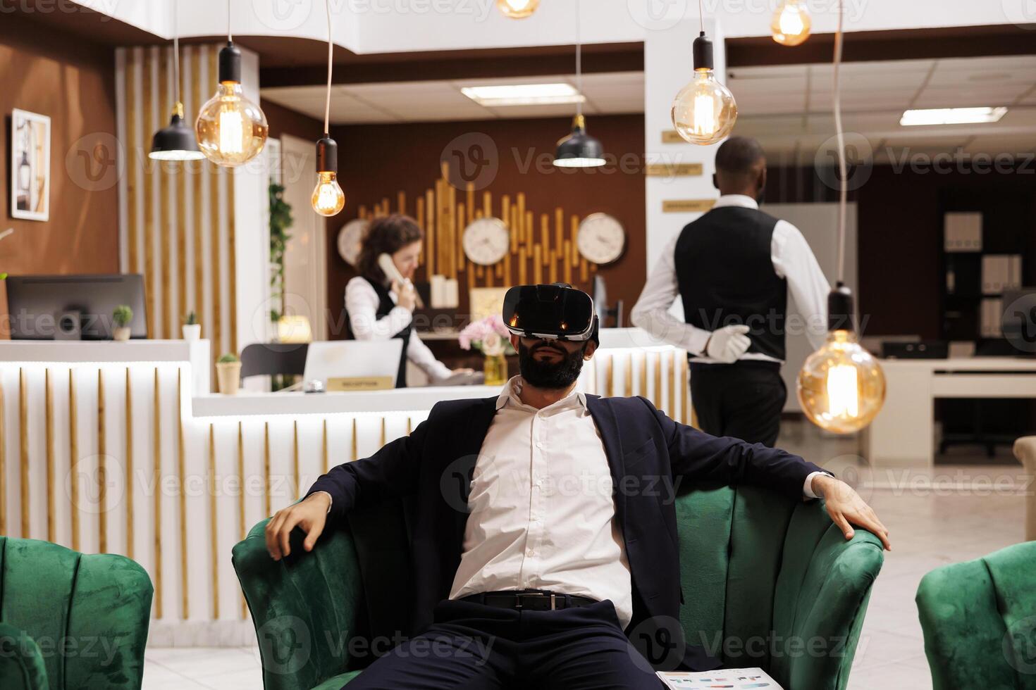 Businessman works with vr headset in hotel lobby, using new 3d interactive vision glasses before doing check in process. Young adult with virtual reality technology on business trip. photo