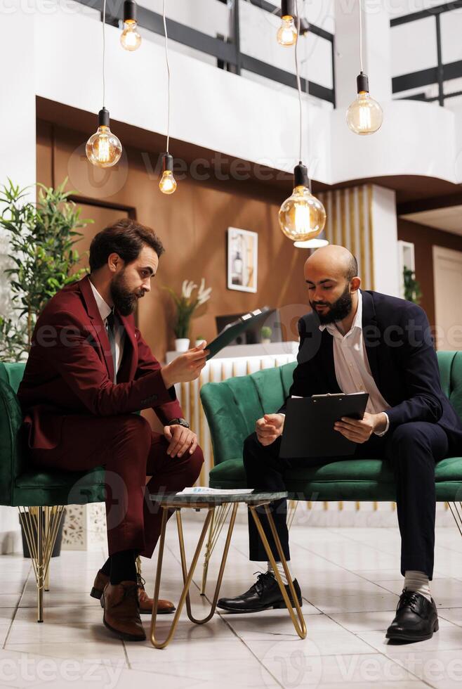 Team undertake fruitful exchange of ideas, leveraging their collective corporate expertise. Business travellers in suits checked the formal conference attire, attention to detail and professionalism. photo