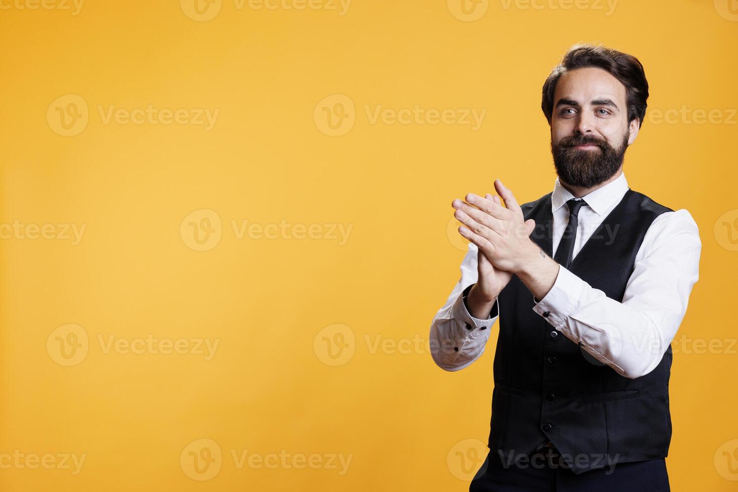 Smiling butler clapping hands in studio, feeling cheerful after congratulating person for success. Young adult with waiter profession applauding and cheering for someone, confidence boost. photo