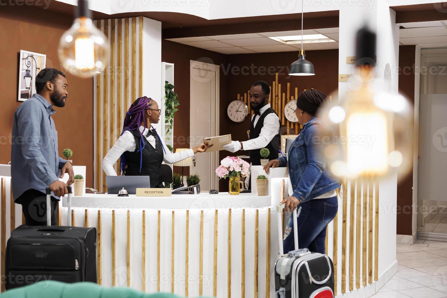 African American couple man an woman standing at hotel reception checking in at reception, waiting for room key or access card. Front desk staff managing guest check-in or check-out process photo