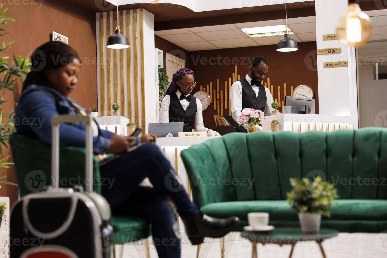 African American front desk staff working together behind reception counter, maintaining guest records and book reservations, hotel employees waiting for tourists at resort. Hospitality industry photo