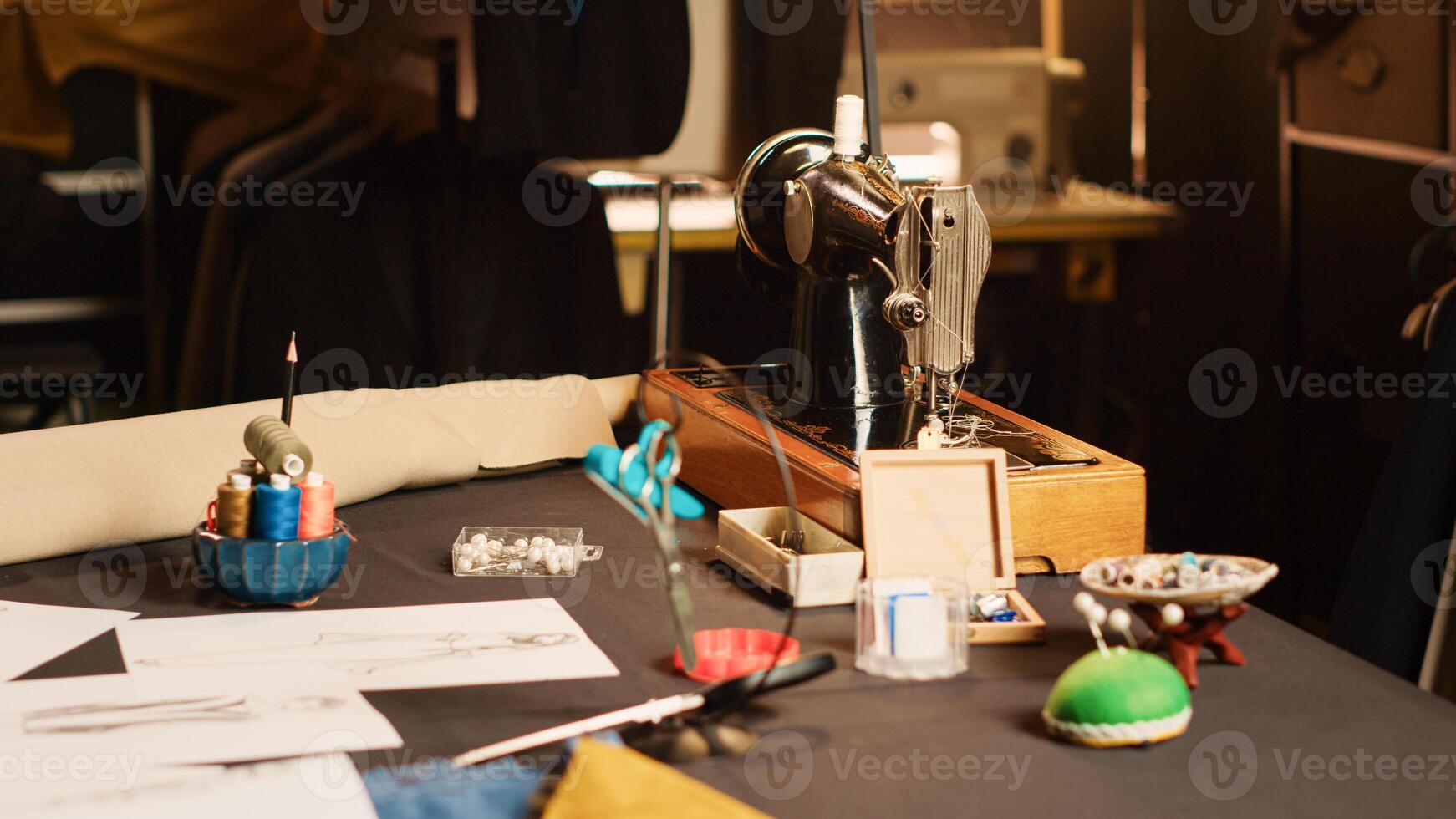 Industrial sewing machine and needles in fashion atelier, luxury craftsmanship with tailoring industry tools in workshop. Workstation with fabric and garments, manufacturing process. Close up. photo