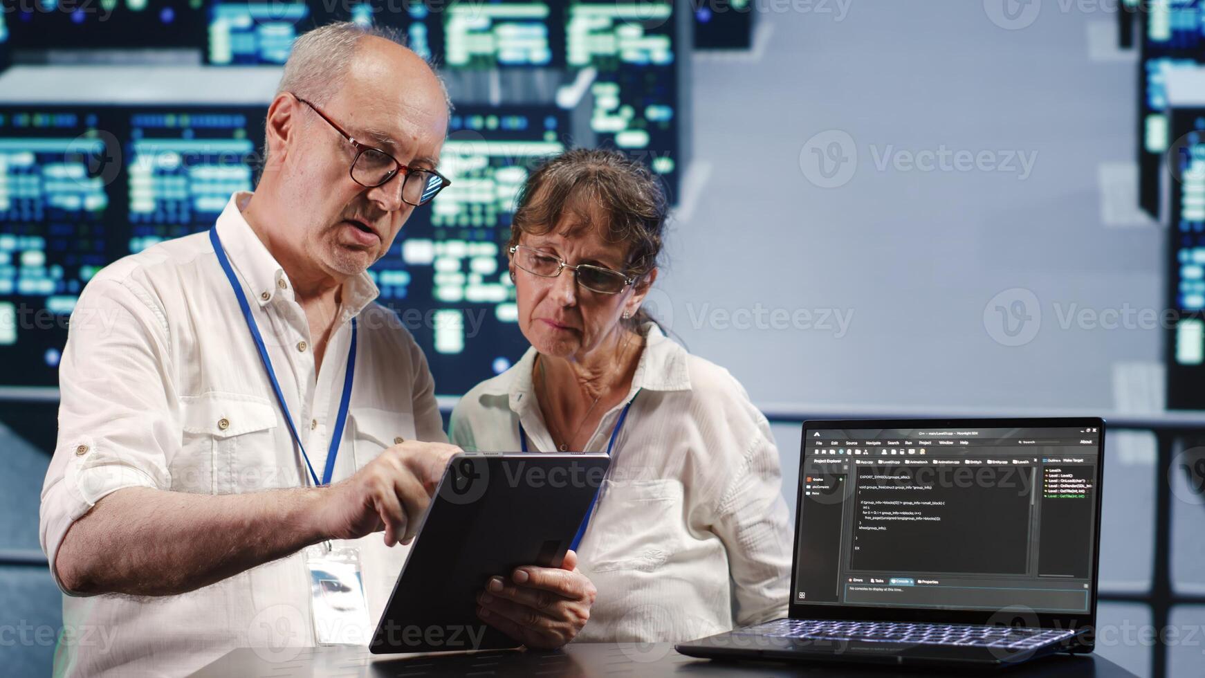 Data storage company executives solving tasks on tablet while running scripts on laptop terminal. Proficient tech support workers amidst servers, accessing databases and manipulating lines of code photo