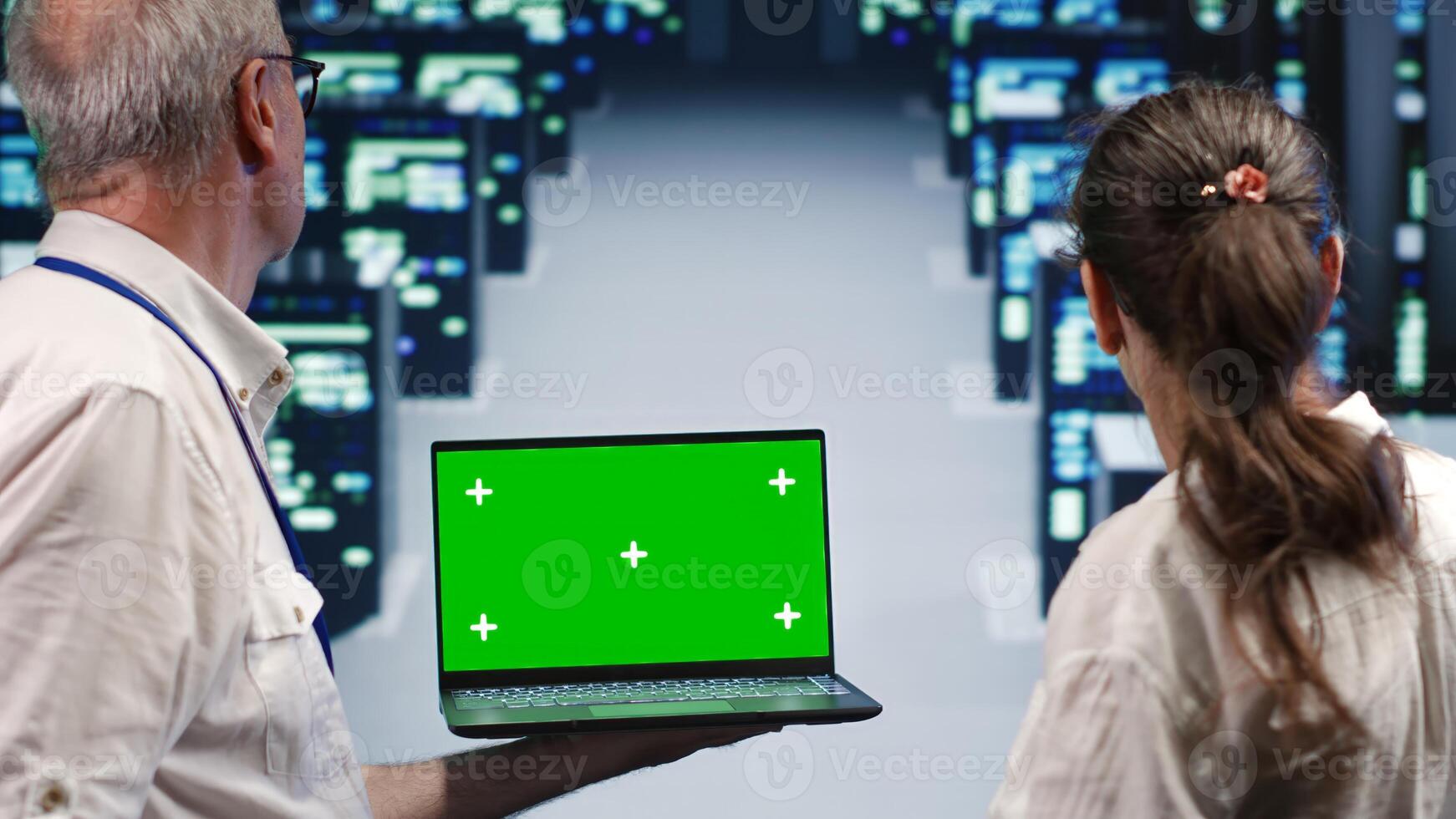 Skilled specialists looking around high tech data center, using mockup laptop to crosscheck disaster recovery plan and assess server units in need of replacement, preventing problems photo