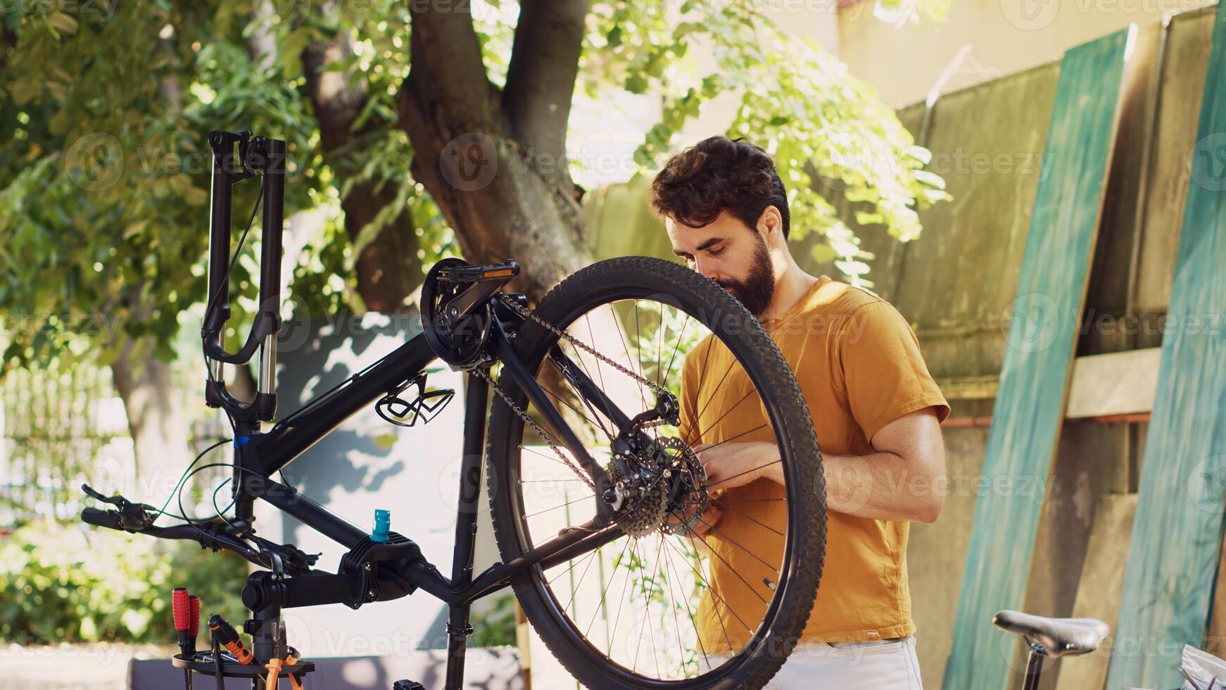 Active man outside demonstrating commitment to repairing and securing bicycle components for summer cycling leisure. Caucasian male selecting professional equipment for bike maintenance. photo