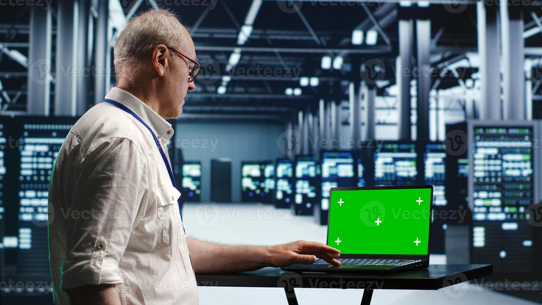 Developer in server room expertly managing data while navigating through industrial mainframes. Expert ensuring flawless cybersecurity guard, optimizing systems using green screen laptop photo