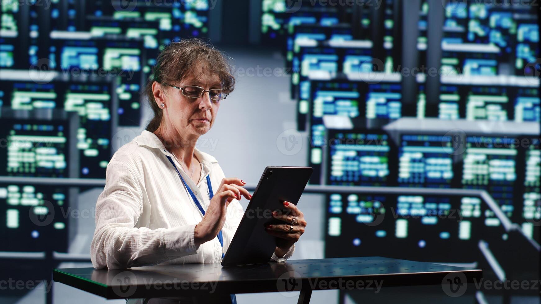 Precise serviceman in cloud computing company housing high end servers capable of quickly and efficiently performing complex computations and data analysis, using tablet to root out blips photo