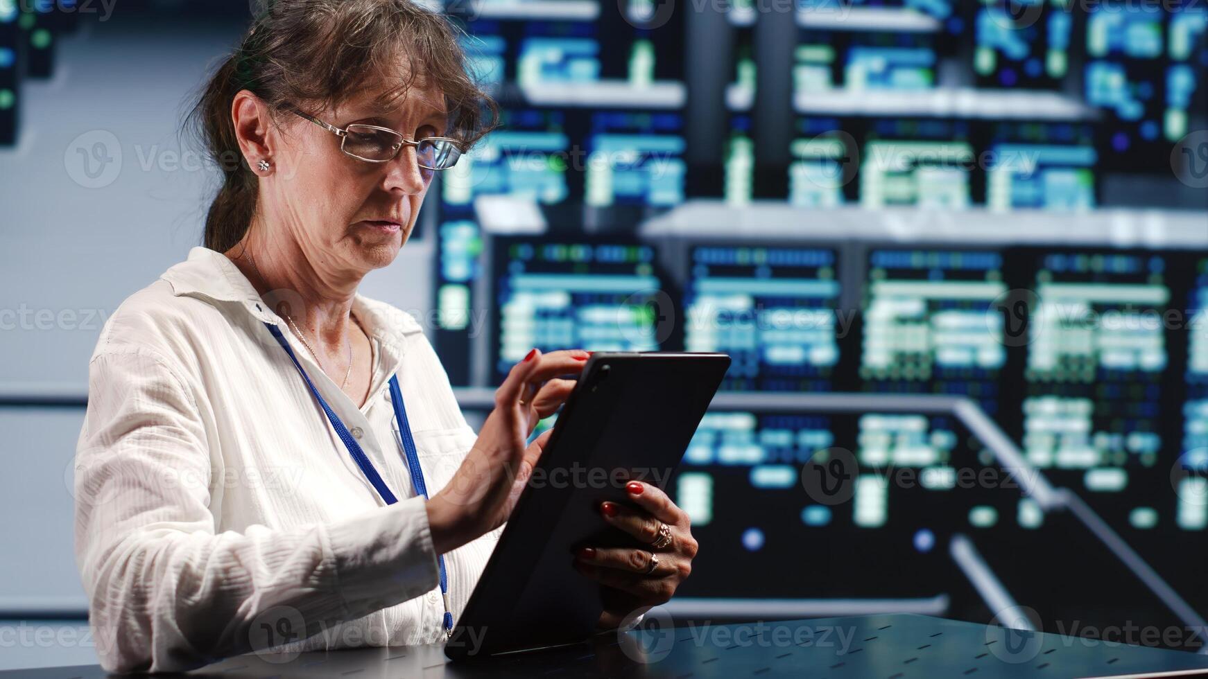 Meticulous mechanic in cloud computing business housing high end servers capable of quickly and efficiently performing complex computations and data analysis, using tablet to cancel disruptions photo