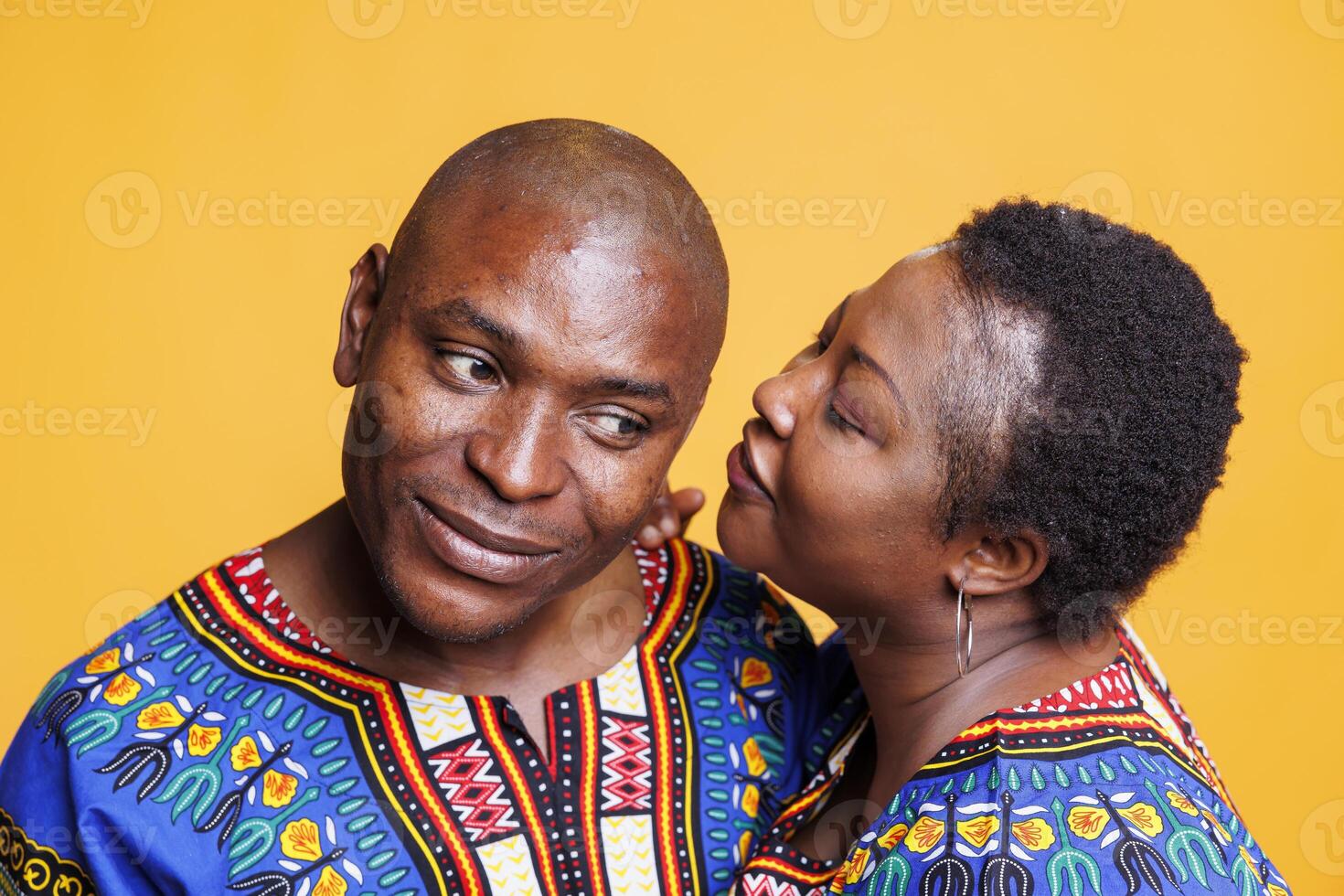 Black man and woman partners exchanging private conversation. African american woman wearing ethnic clothes whispering in husband ear while man listening to wife telling gossip photo