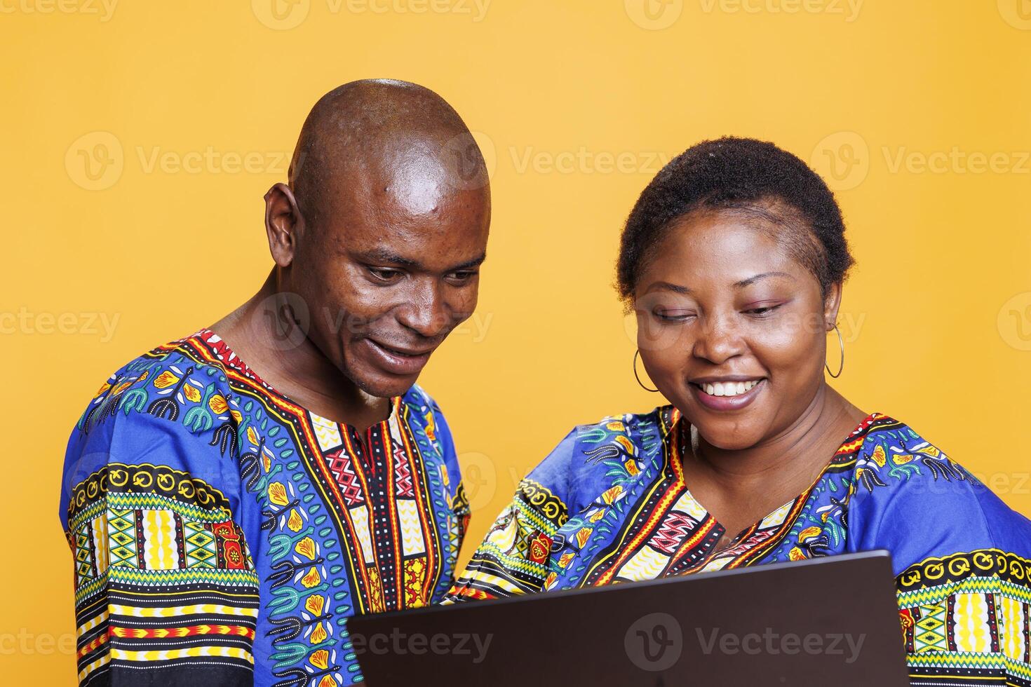 Cheerful black man and woman with smile on face using laptop and enjoying internet leisure activity together. Smiling couple using portable computer, checking information online photo
