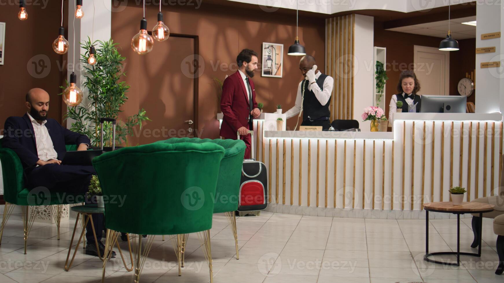 Businessman begins registration process by discussing with hotel staff at front desk reception. Executive manager is eager to visit the venue and prepare for upcoming global conference. photo