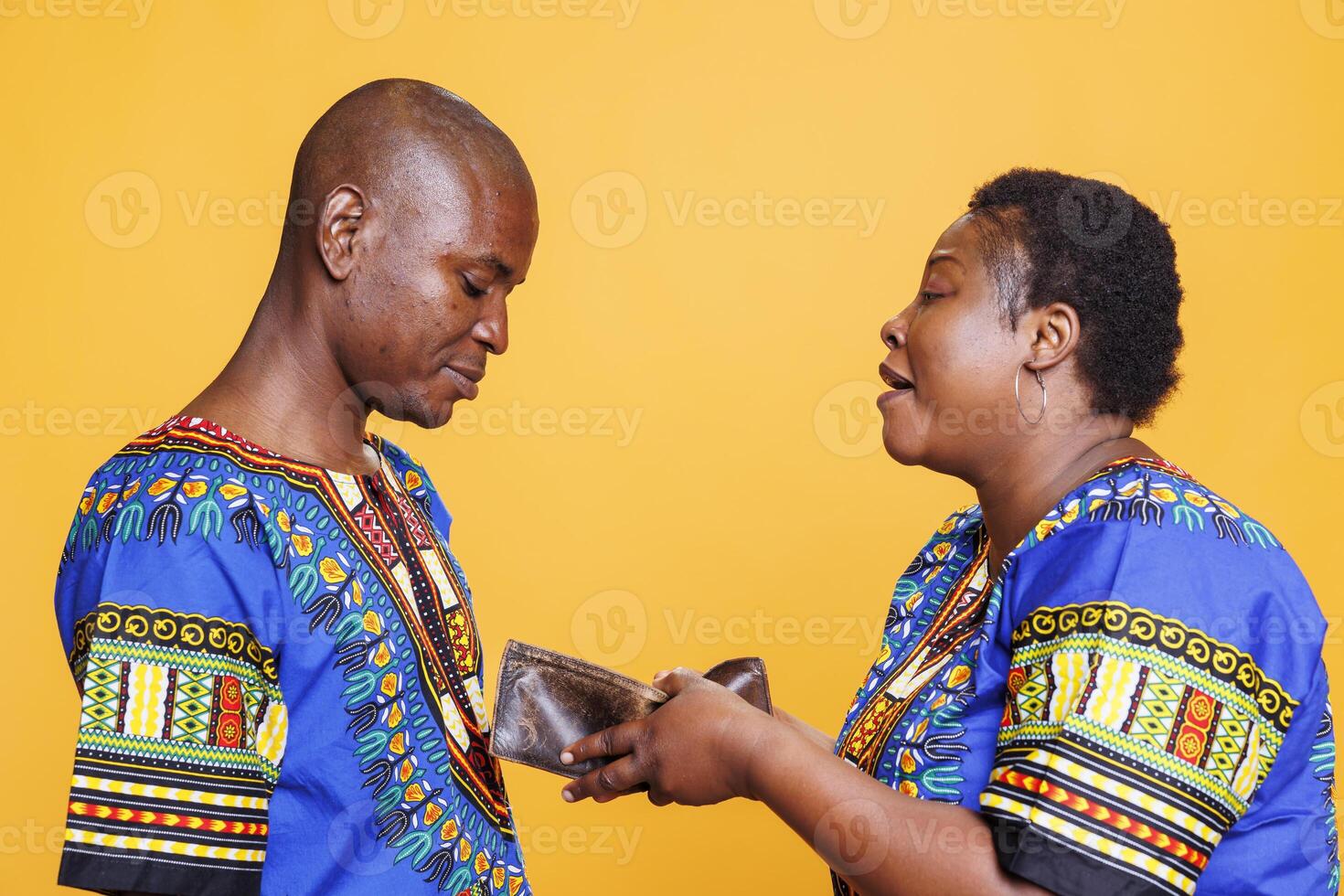 Woman holding open empty wallet with no finance and shouting at unhappy husband. African american couple having conflict while discussing financial problem and displaying purse with no money photo