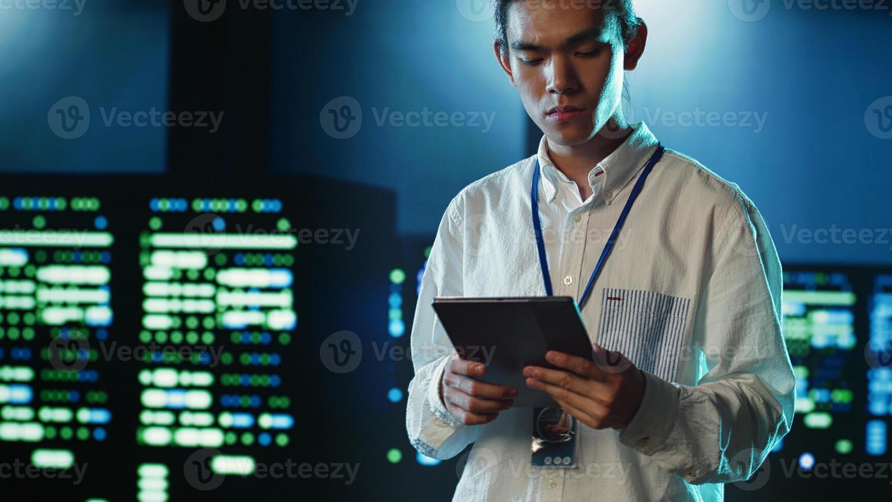 Licensed programmer strolling through server rows providing processing resources for different workloads. Asian IT developer monitoring supercomputers tasked with solving complex operations photo