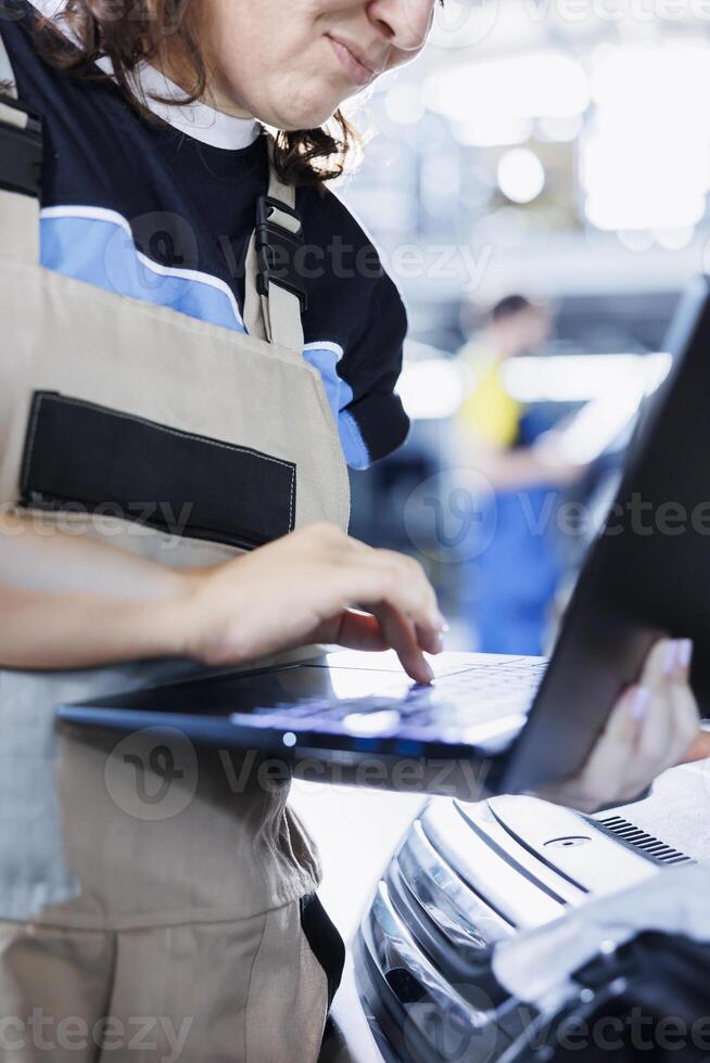 Capable mechanic in car service orders new engine for damaged vehicle using laptop. Garage employee looking for components on internet to replace old ones in out of order automobile, close up photo