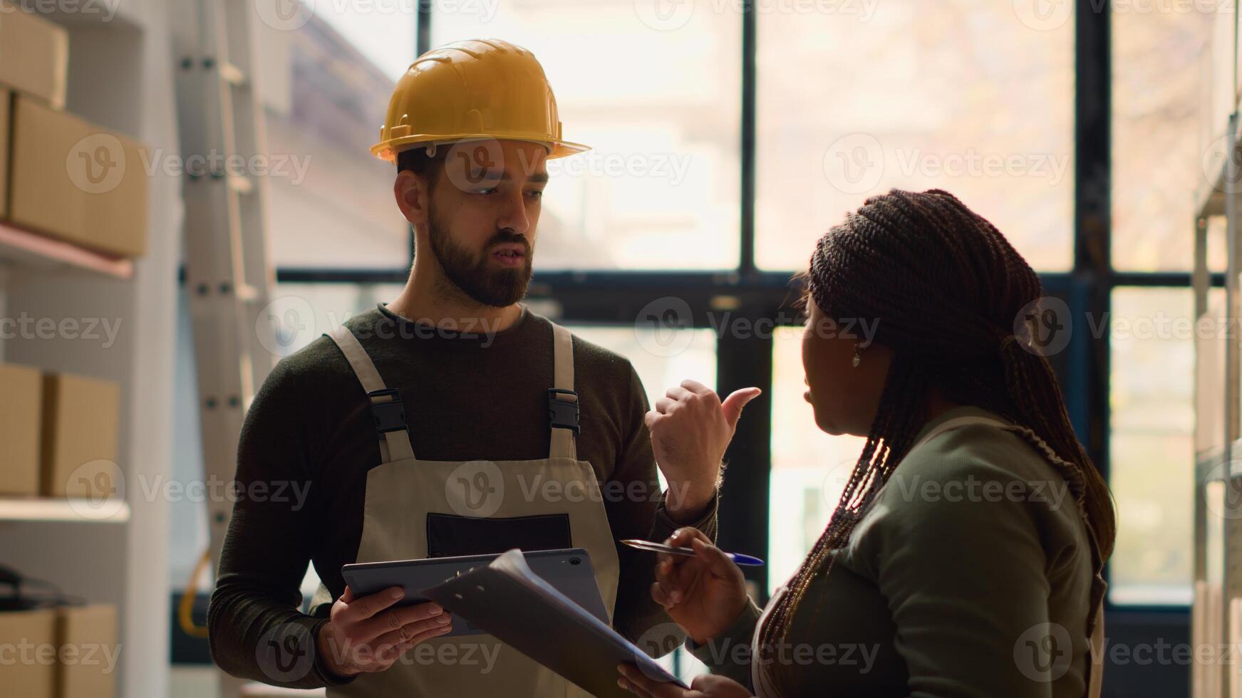 Proficient coworkers performing warehouse inventory controls, discussing ways of keeping quality standards high. Qualified experts preparing to ship parcels to customers, crosschecking delivery info photo