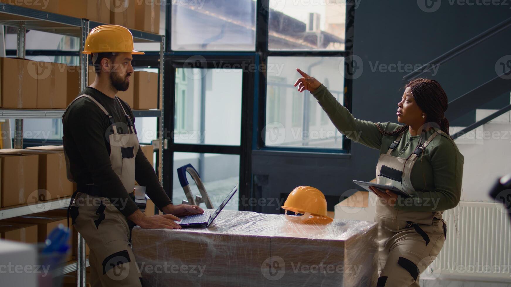 Workers undertaking warehouse inventory evaluation, keeping quality standards high. Experts in storage room check labels on products, crosschecking delivery info using laptop photo