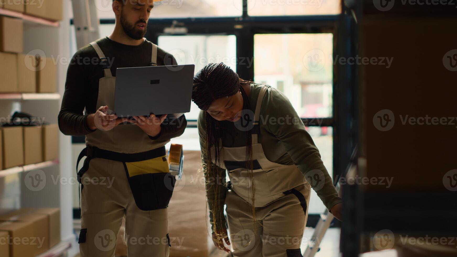 Precise logistics coordinator and worker perform warehouse inventory controls, keeping quality standards high. Capable experts in storage venue prepare to ship parcels, crosschecking delivery info photo